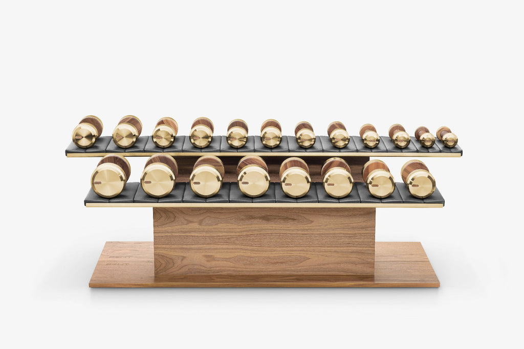 Wooden two-tier stand with rows of gold and bronze dumbbells on dark padded shelves