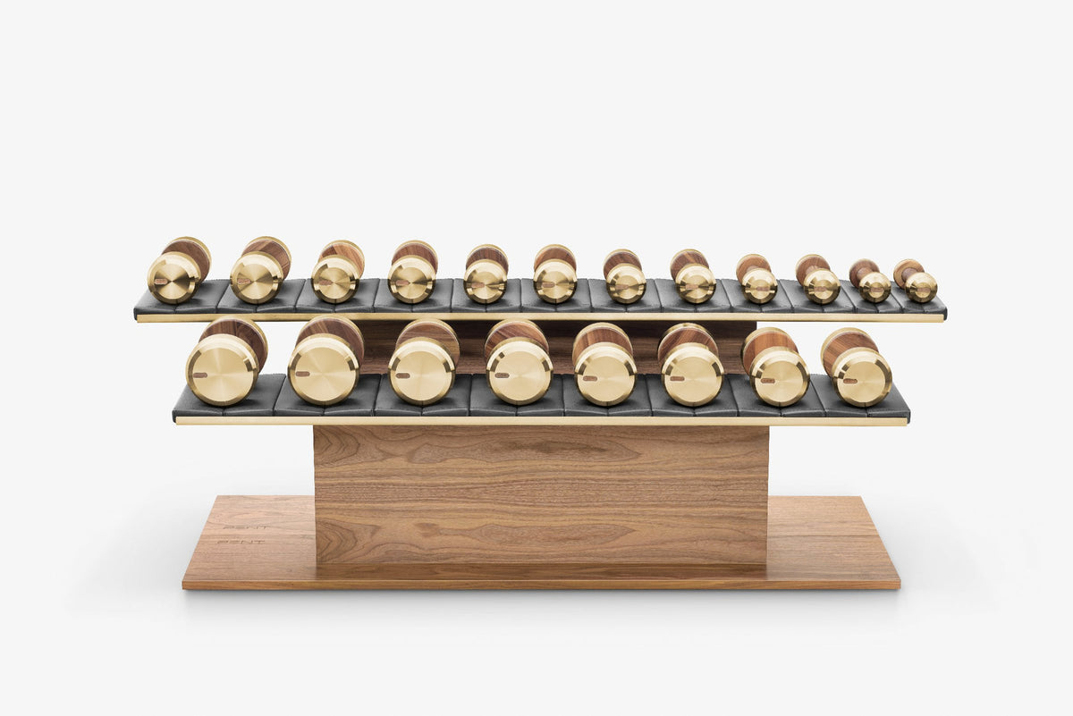Wooden two-tier stand with rows of gold and bronze dumbbells on dark padded shelves