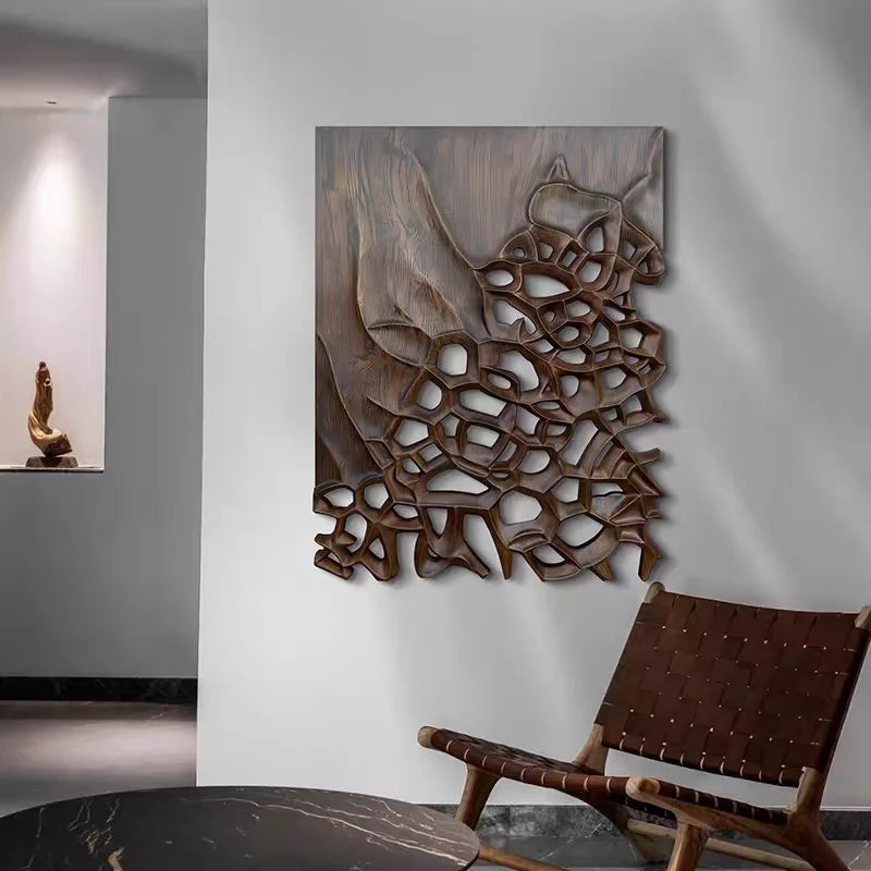 Layered brown wall panel with irregular open shapes above a lounge chair and dark table