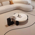 Travertine-finish coffee table with angular base paired with a glass side table in a styled living room