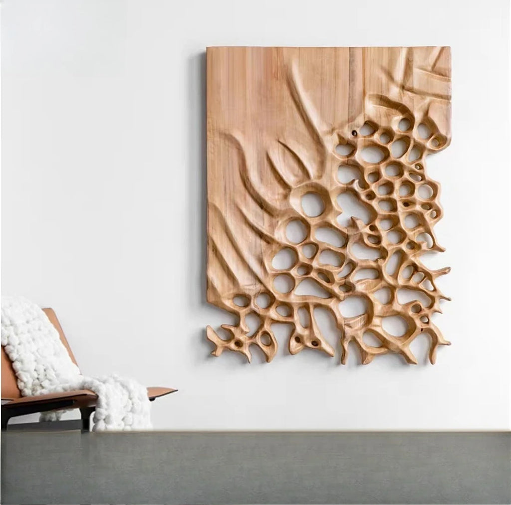 Carved brown wall panel with organic holes hanging above a gray surface and lounge chair