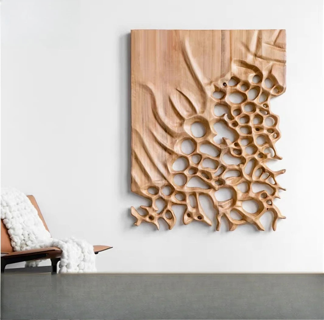 Carved brown wall panel with organic holes hanging above a gray surface and lounge chair
